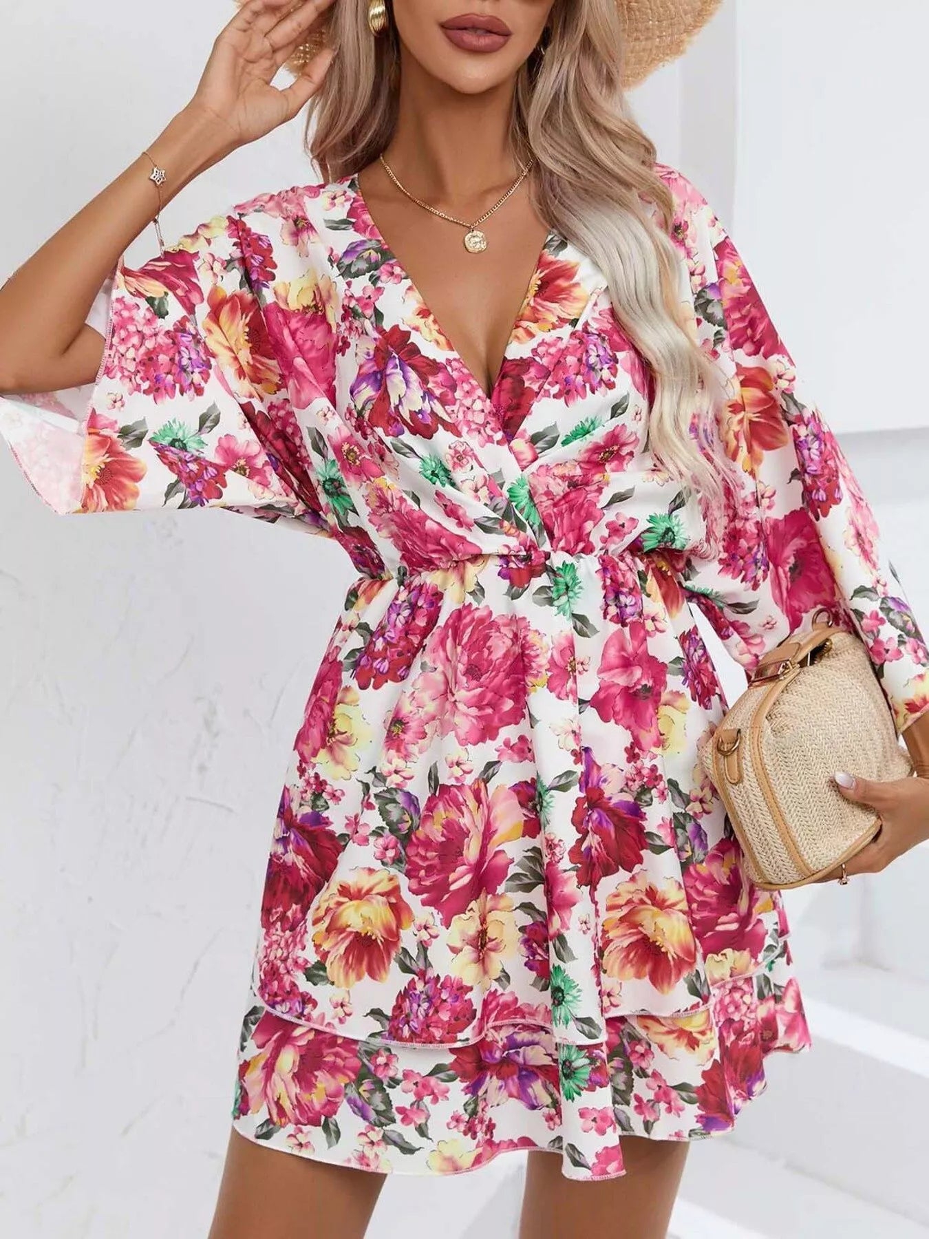 Floral mini dress with a surplice V-neckline, flowy sleeves, tiered skirt, and bright pink floral print.