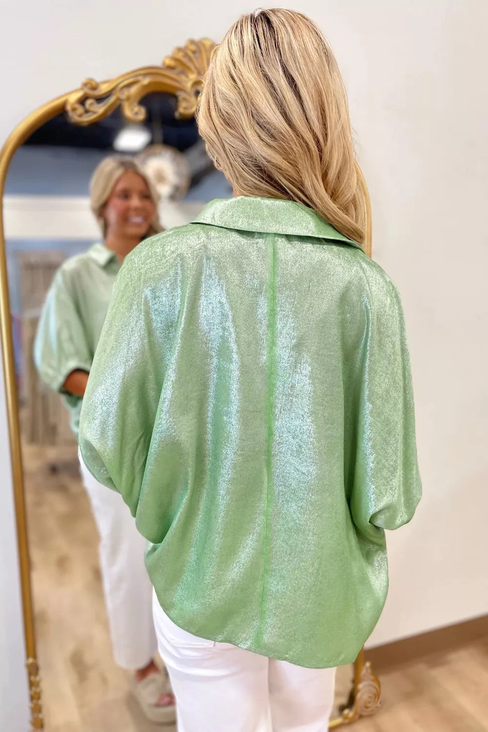 Shimmery collared puff sleeve top with a split neckline, relaxed fit, and satin-like finish styled with white pants.
