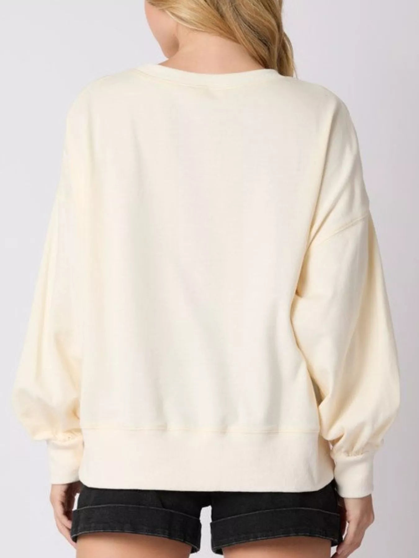 Woman wearing a cream sweatshirt with sequin gingerbread men and candy canes — cozy holiday pullover.