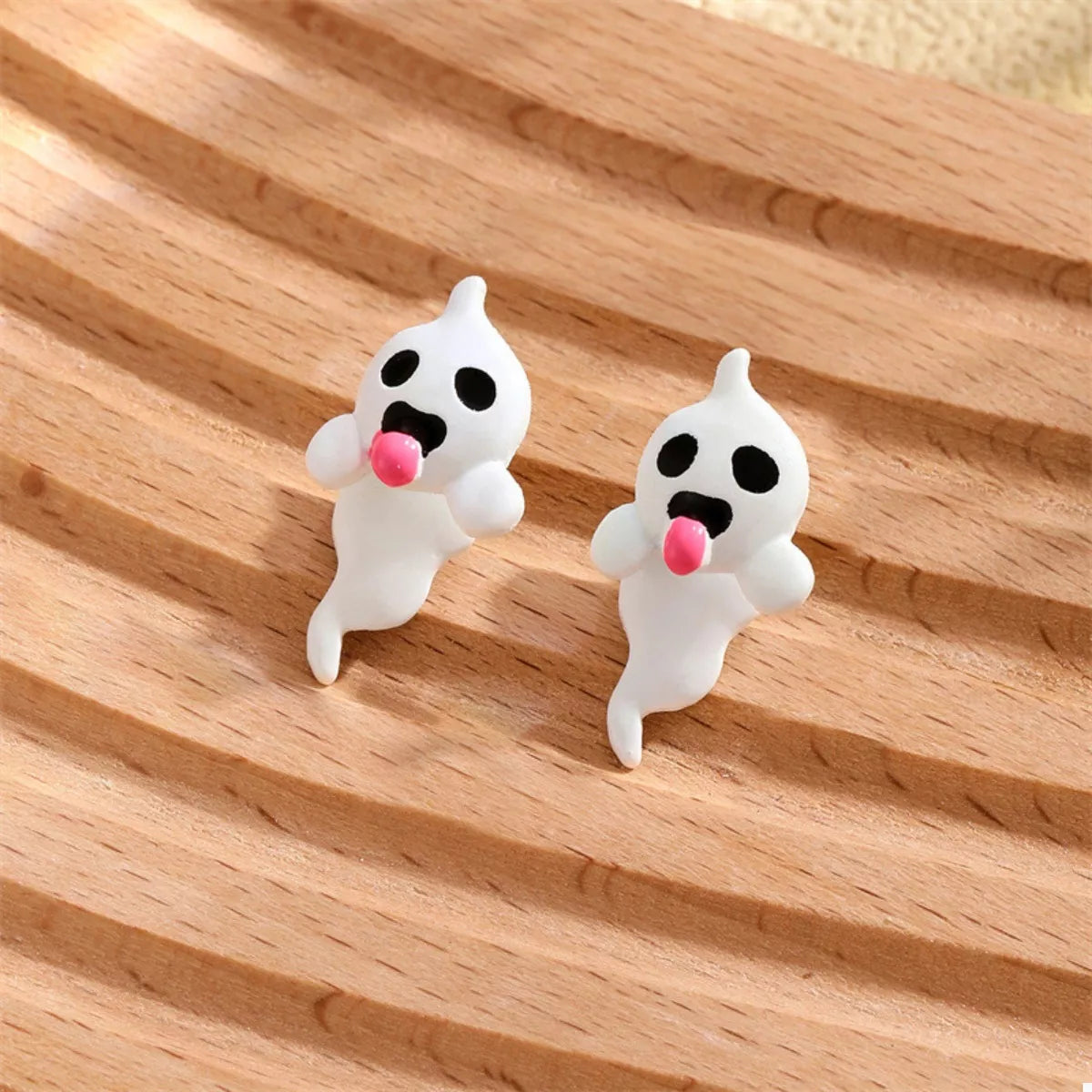 Close-up of a woman wearing glow-in-the-dark ghost earrings featuring white resin ghosts with pink tongues — spooky cute Halloween jewelry from A Whimsical Affair.