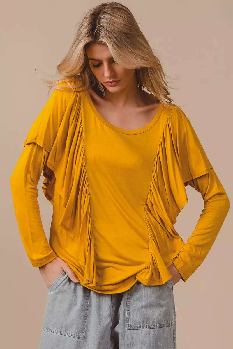 Golden yellow long sleeve top with cascade ruffle overlay, ruched details, round neckline, and slightly stretchy rayon fabric.