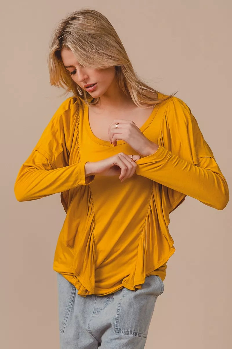 Golden yellow long sleeve top with cascade ruffle overlay, ruched details, round neckline, and slightly stretchy rayon fabric.