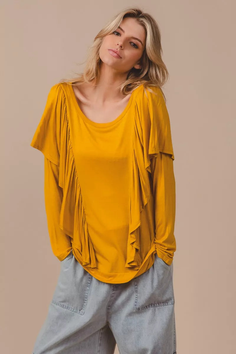 Golden yellow long sleeve top with cascade ruffle overlay, ruched details, round neckline, and slightly stretchy rayon fabric.