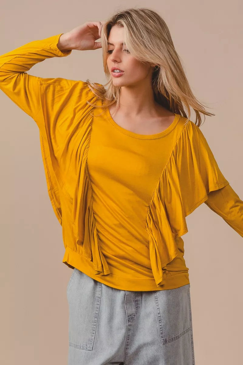 Golden yellow long sleeve top with cascade ruffle overlay, ruched details, round neckline, and slightly stretchy rayon fabric.