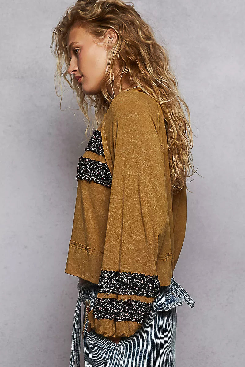 Woman wearing a mustard cropped blouse with patchwork details and balloon sleeves for a boho chic look.