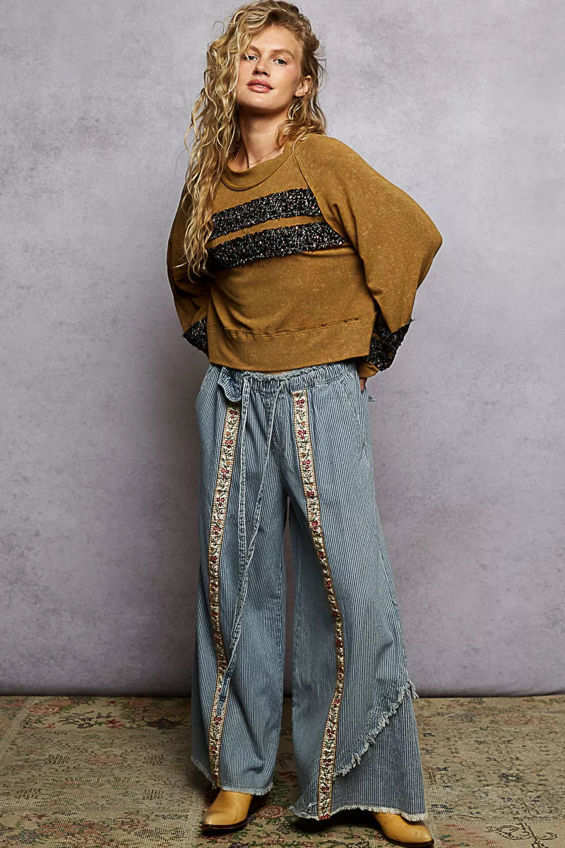 Woman wearing a mustard cropped blouse with patchwork details and balloon sleeves for a boho chic look.