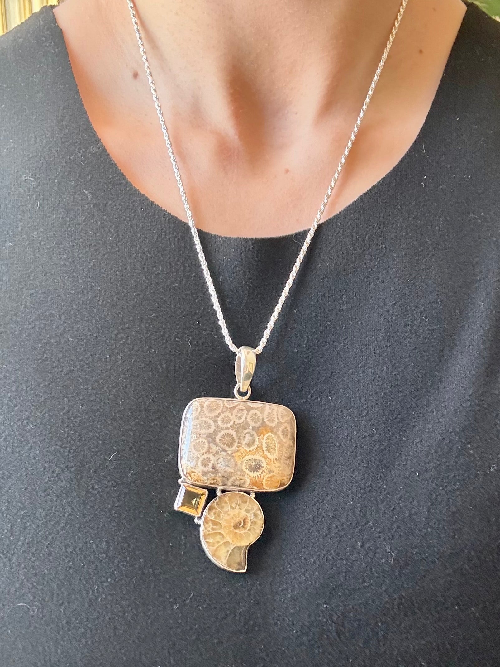 Silver pendant necklace on a person wearing a dark gray shirt