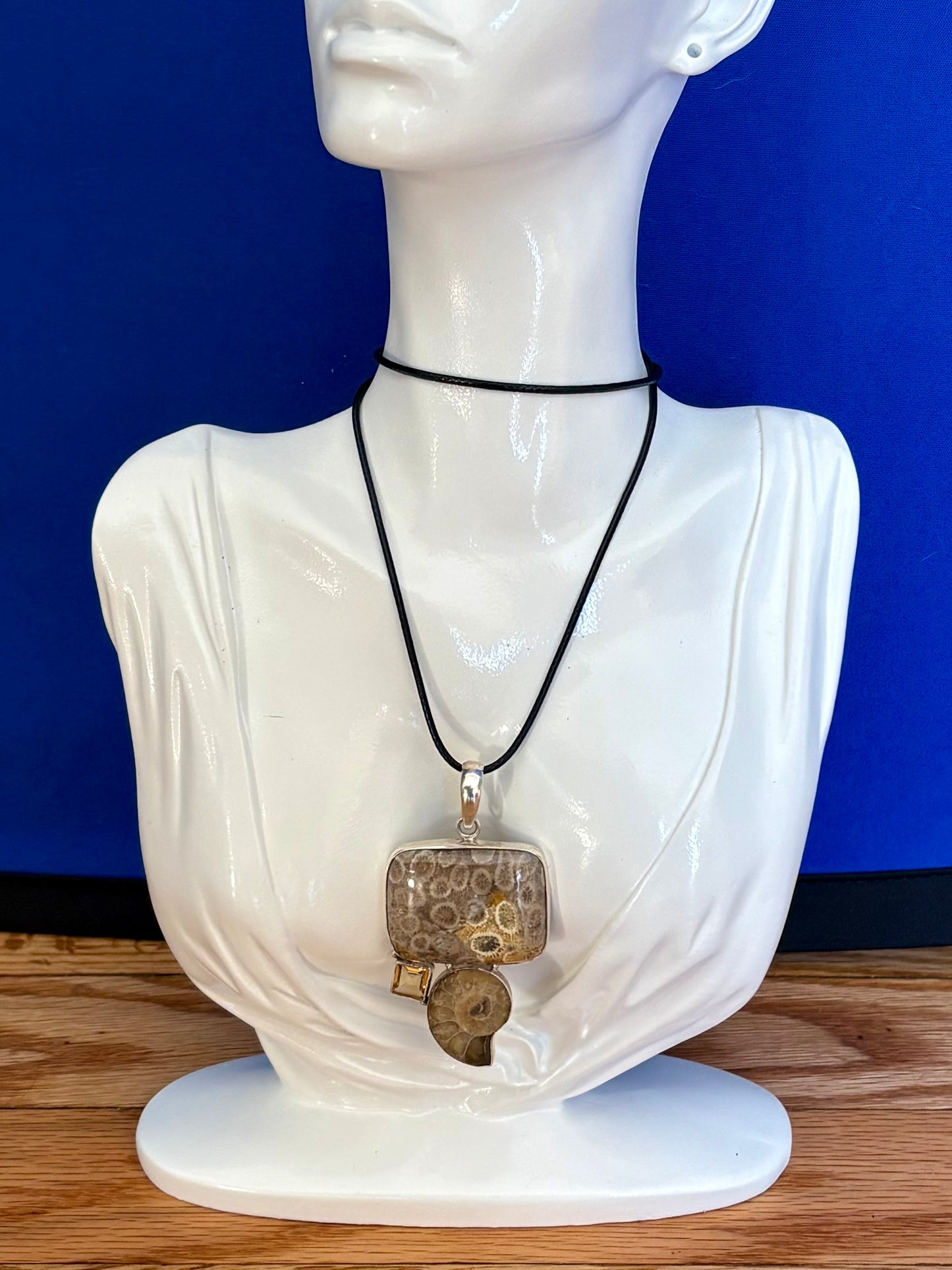 Mannequin wearing a necklace with a pendant against a blue background