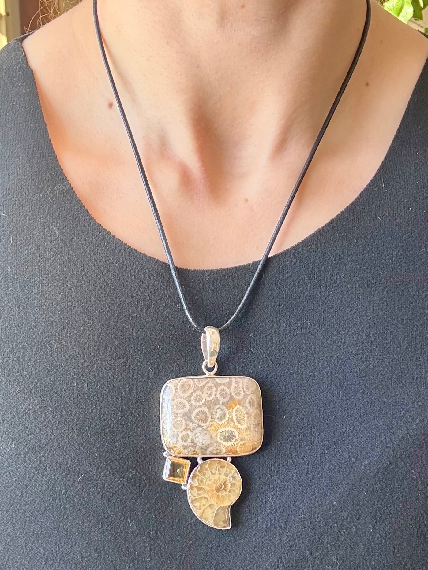 Necklace with a pendant on a person wearing a dark gray top