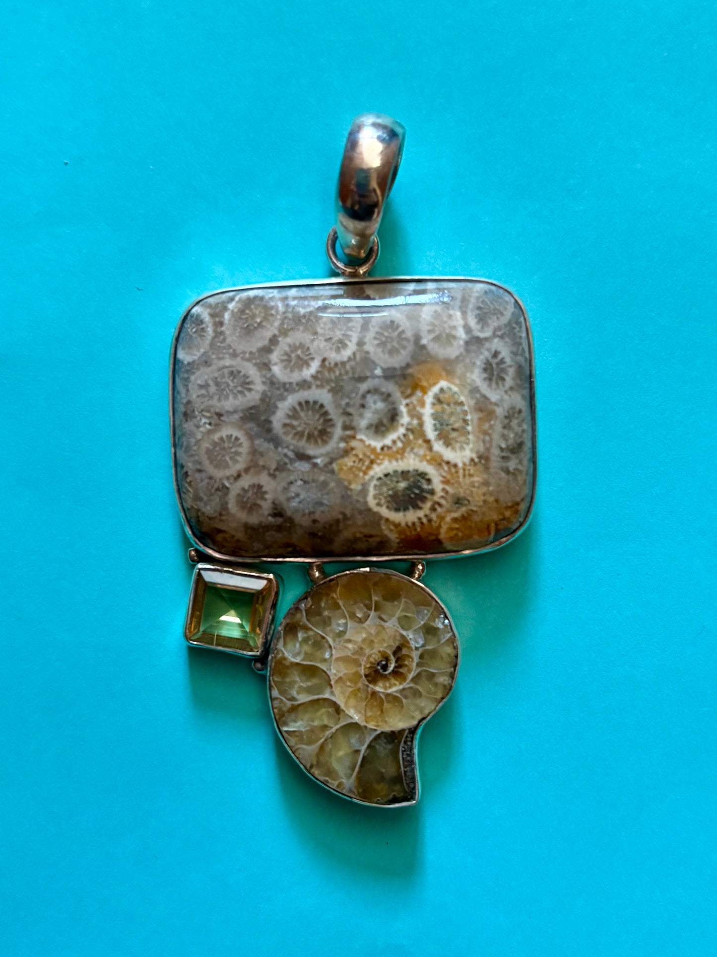 Jewelry pendant with fossil design on a blue background