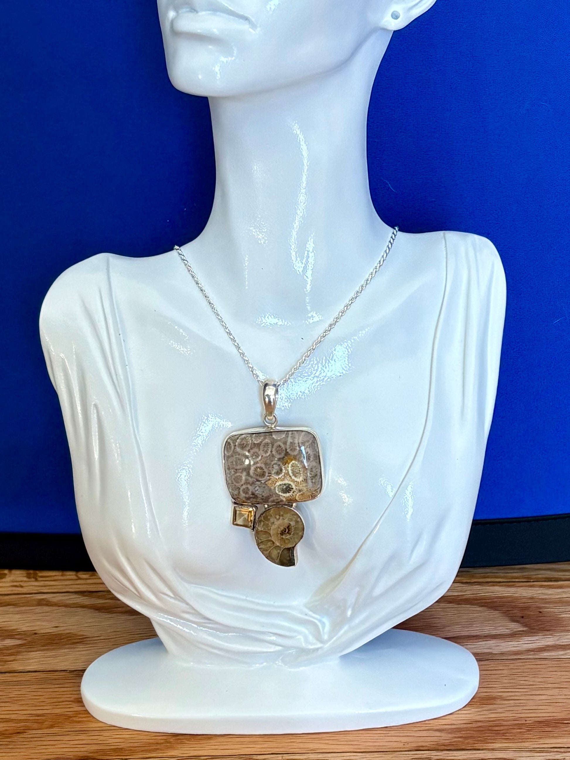 Mannequin wearing a necklace with a large pendant against a blue background