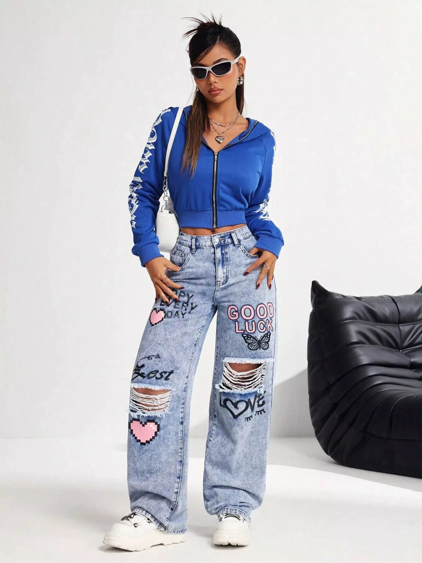 Light wash wide-leg jeans with distressed cutouts, graphic lettering, butterfly detail, and relaxed street-style fit.