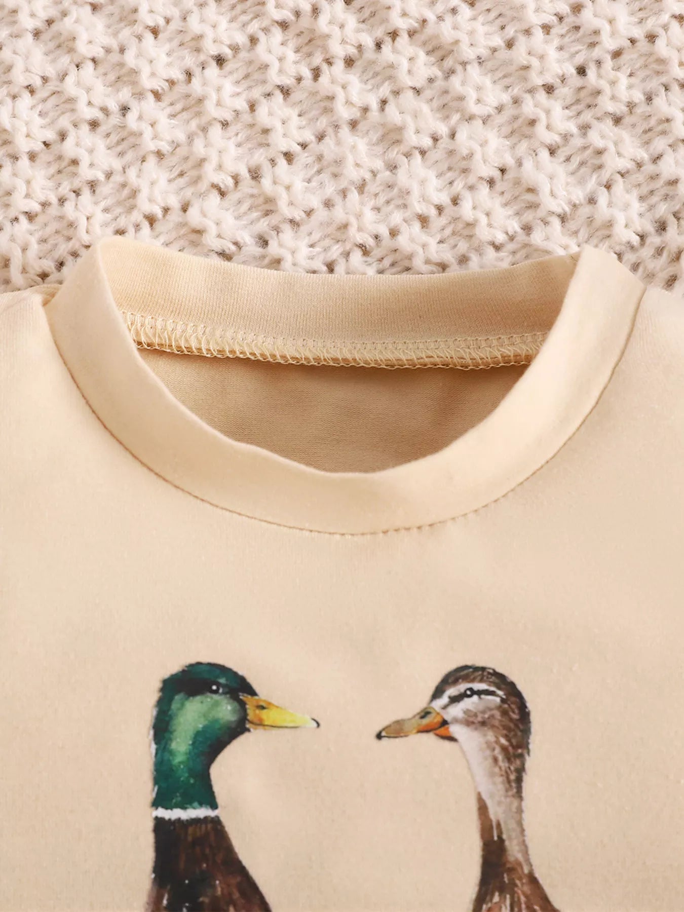 Cream baby romper with “Goose on the Loose” duck graphic, short sleeves, snap bottom, and soft cotton-blend fabric.