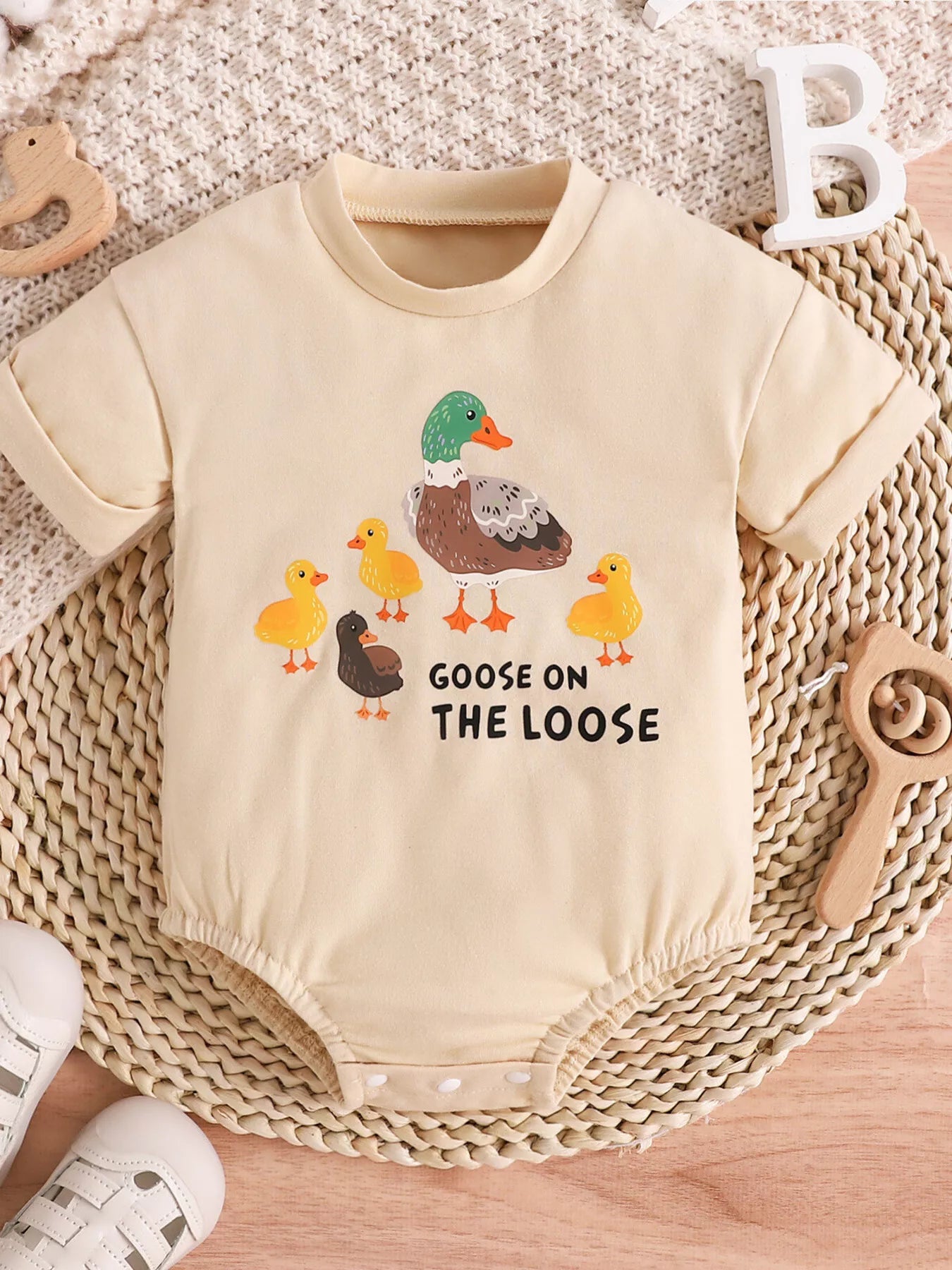 Cream baby romper with “Goose on the Loose” duck graphic, short sleeves, snap bottom, and soft cotton-blend fabric.