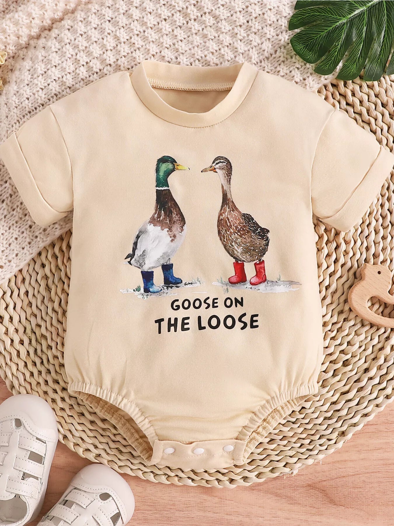 Cream baby romper with “Goose on the Loose” duck graphic, short sleeves, snap bottom, and soft cotton-blend fabric.