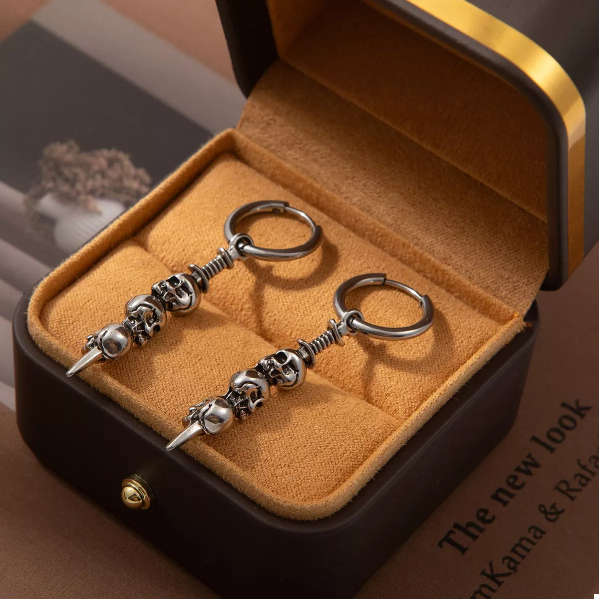 Close-up of silver skull drop earrings with stacked skull design hanging from small hoops — gothic Halloween jewelry from A Whimsical Affair.