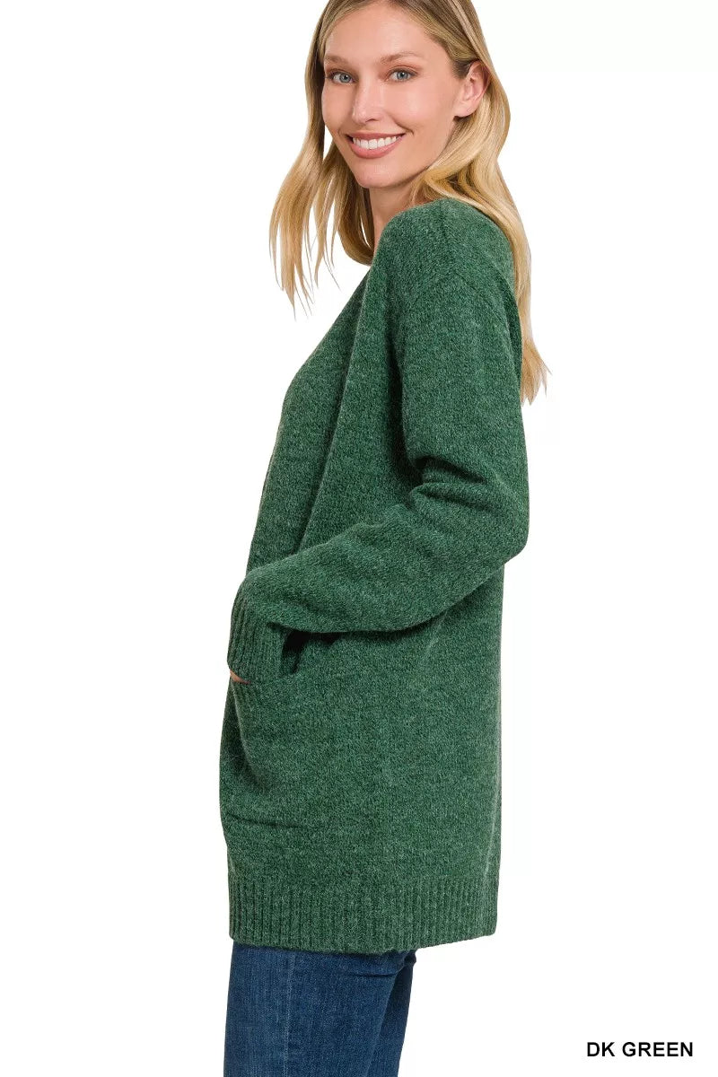 Open-front knit cardigan with front pockets, ribbed trim, long sleeves, and a relaxed slightly stretchy fit styled with jeans.
