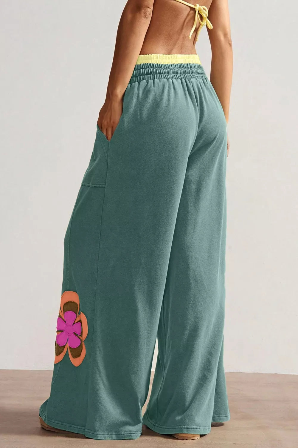 Teal wide-leg sweatpants with drawstring waist, front pockets, and colorful floral appliqué details.
