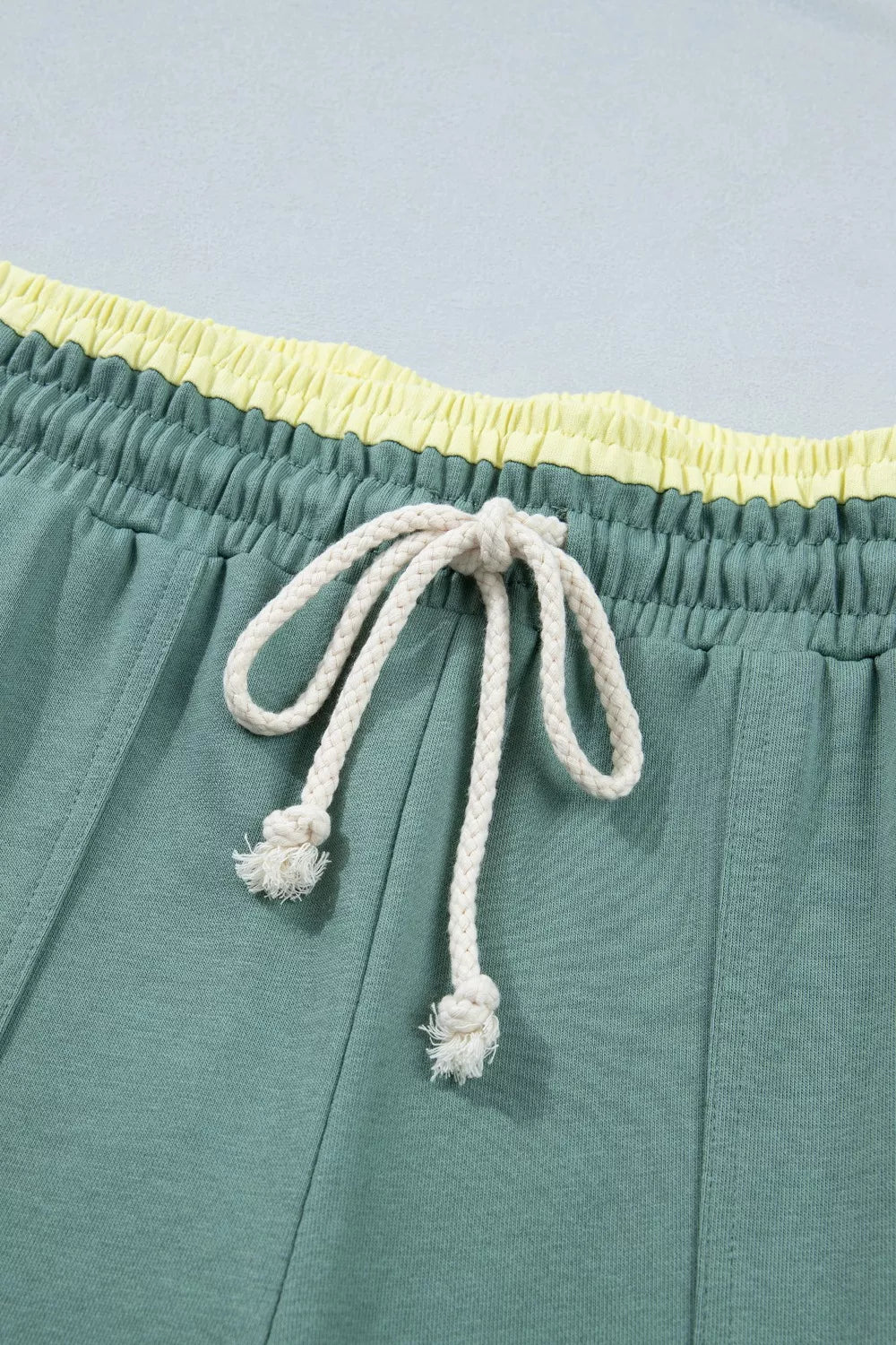 Teal wide-leg sweatpants with drawstring waist, front pockets, and colorful floral appliqué details.