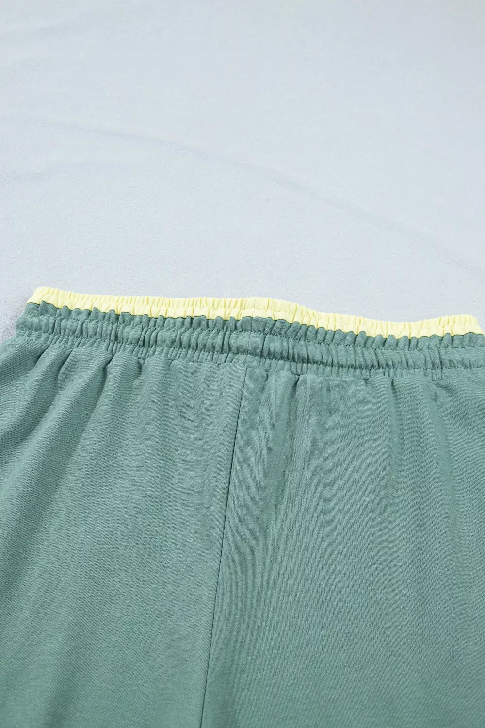Teal wide-leg sweatpants with drawstring waist, front pockets, and colorful floral appliqué details.