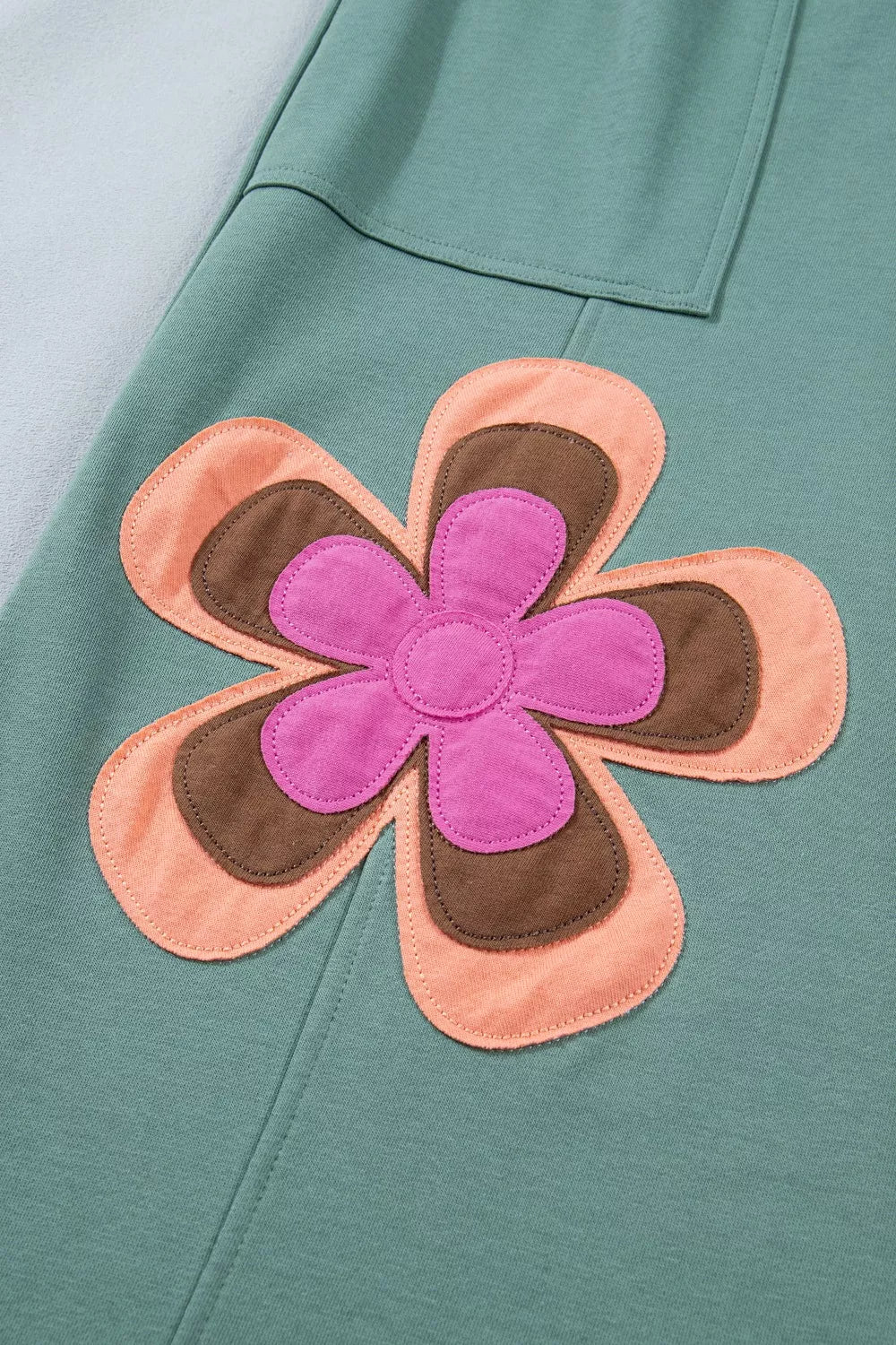 Teal wide-leg sweatpants with drawstring waist, front pockets, and colorful floral appliqué details.
