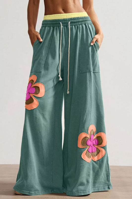 Teal wide-leg sweatpants with drawstring waist, front pockets, and colorful floral appliqué details.