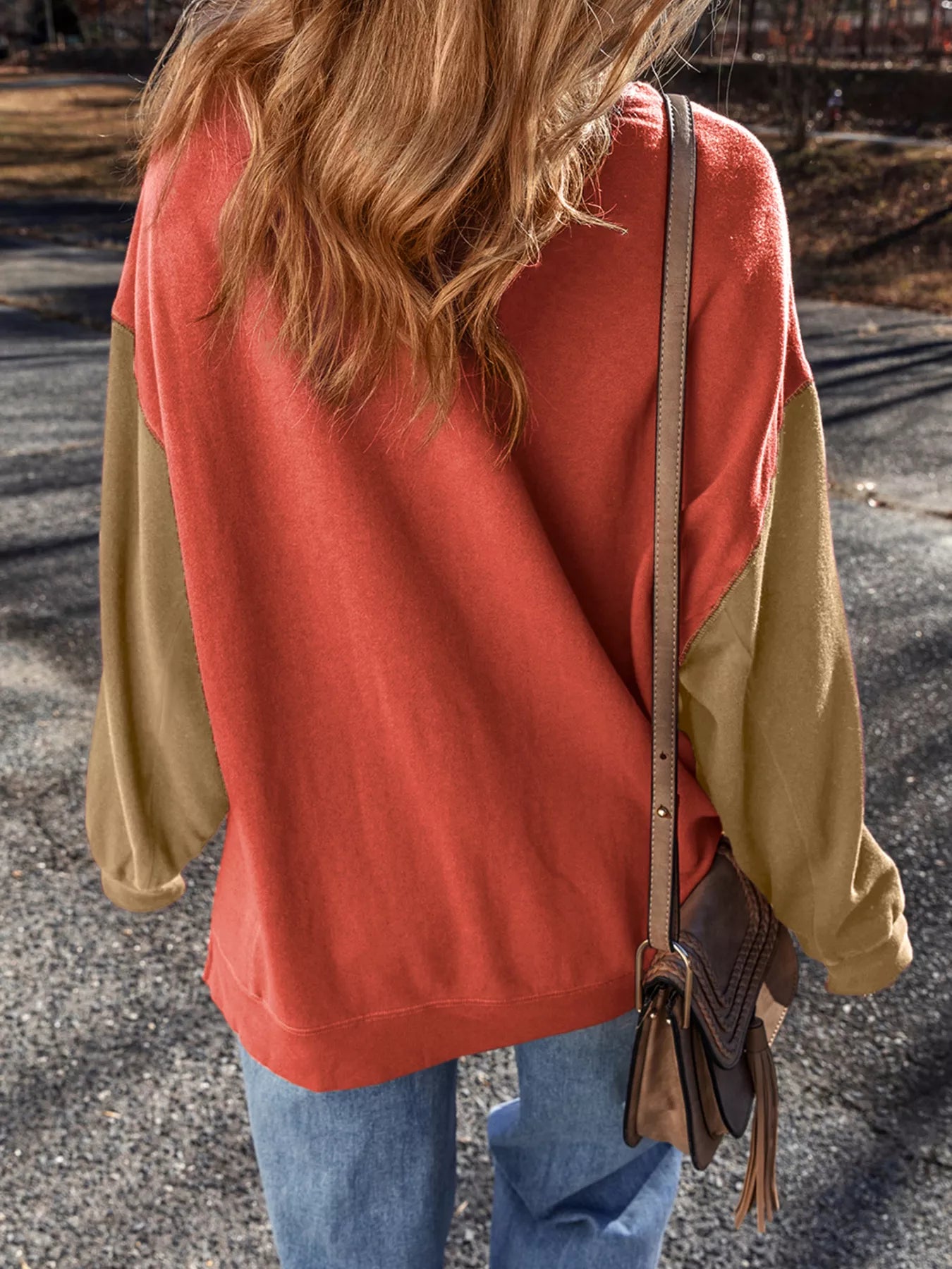 Woman wearing a rust-orange sweatshirt with sequin white ghosts topped with pink bows — festive and cozy Halloween top from A Whimsical Affair.