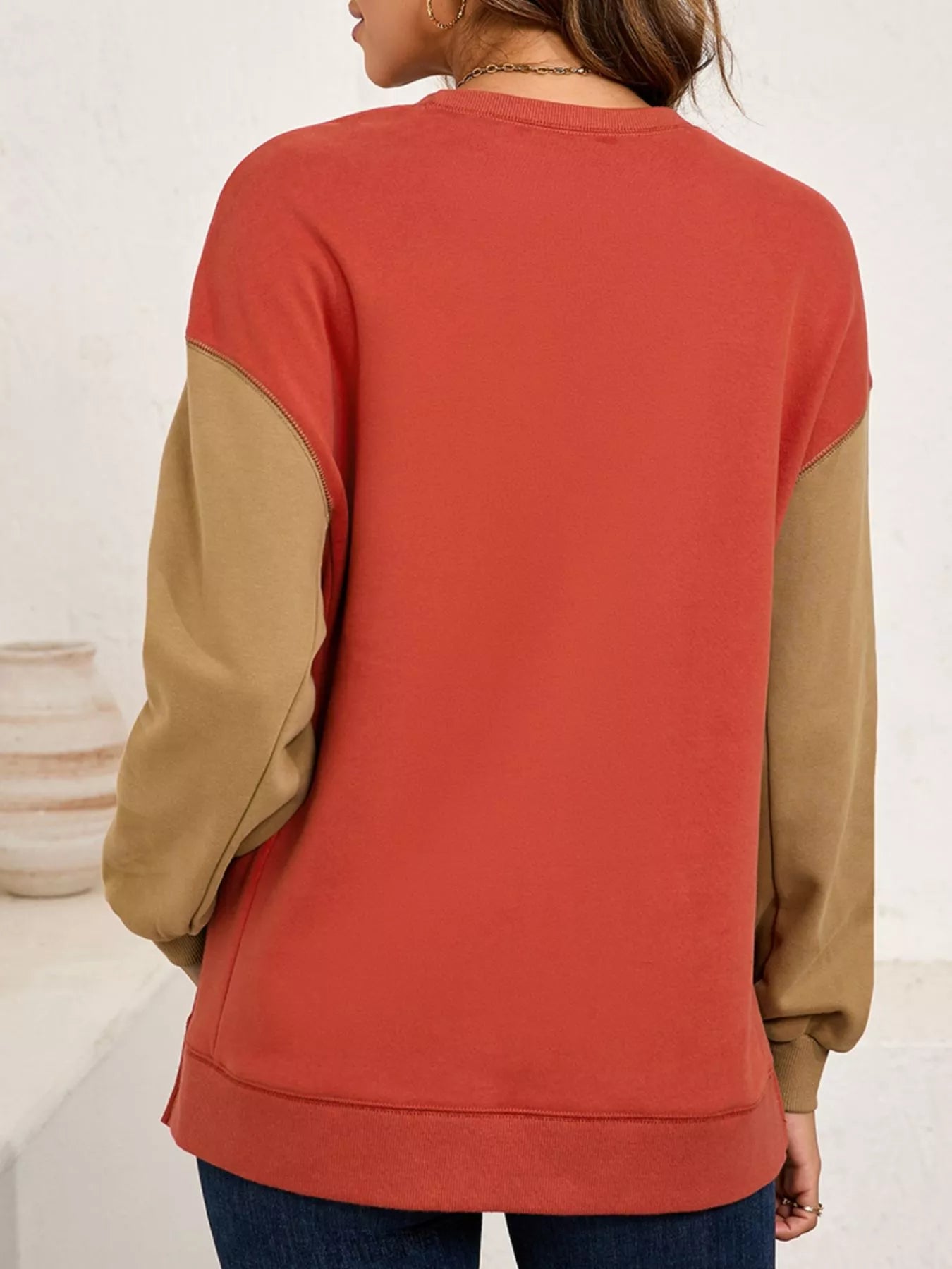 Woman wearing a rust-orange sweatshirt with sequin white ghosts topped with pink bows — festive and cozy Halloween top from A Whimsical Affair.