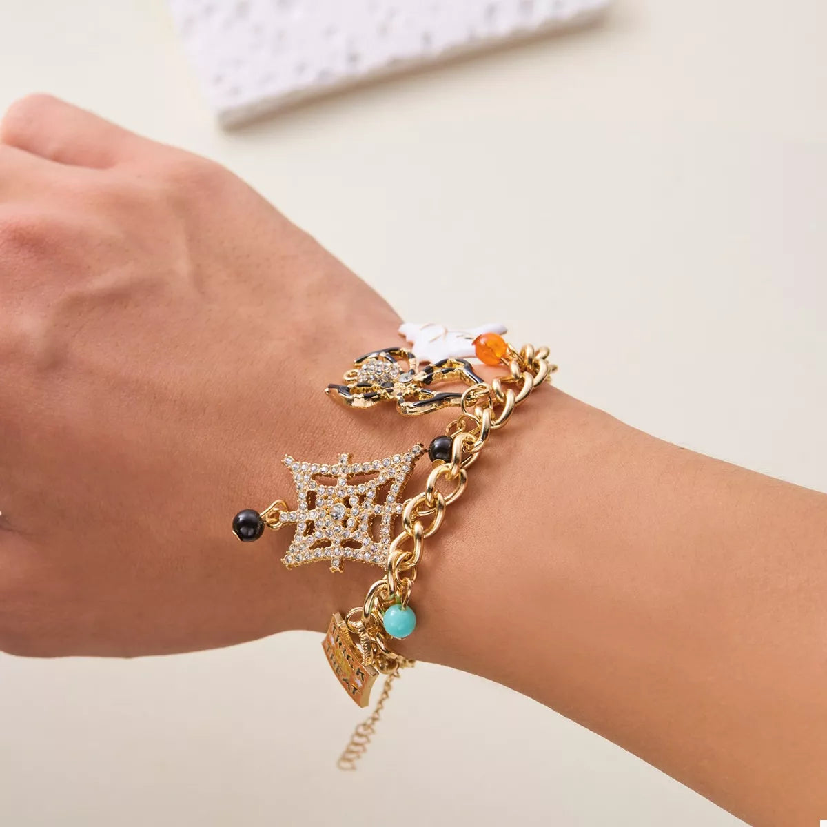 Haunting Charms Halloween Bracelet – 18K gold-plated bracelet with spiderweb, gem, and Halloween-themed charms.