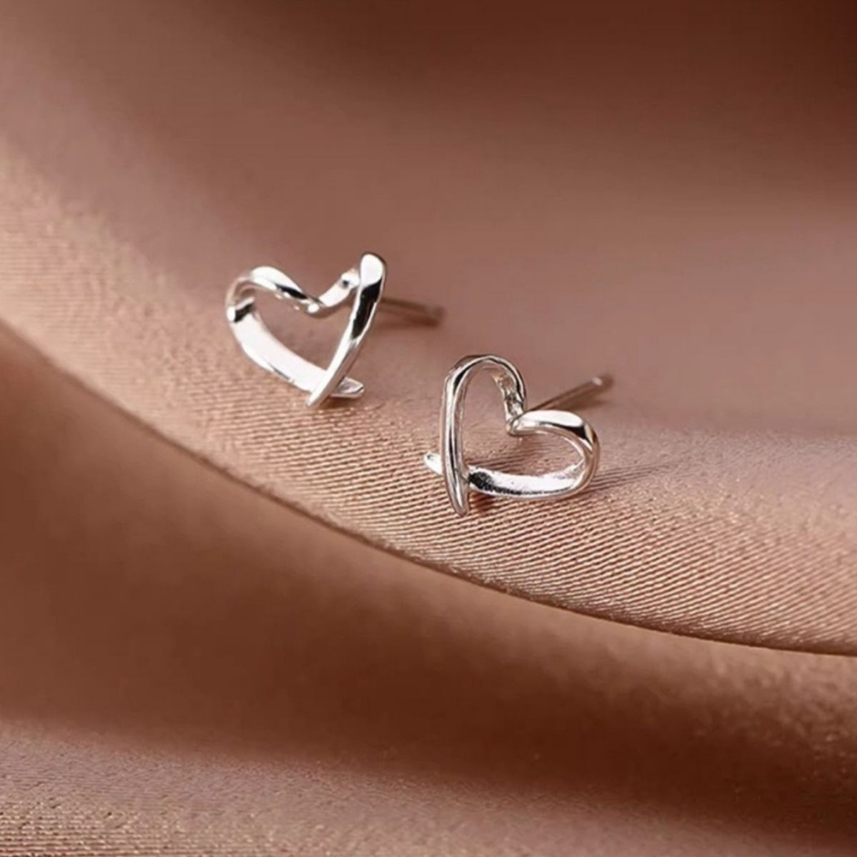 Woman wearing delicate 925 sterling silver open heart stud earrings