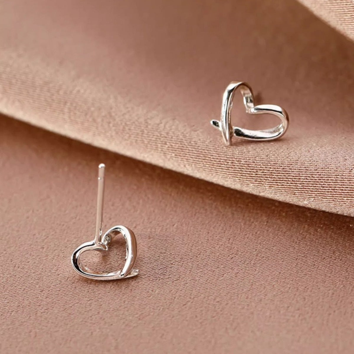 Woman wearing delicate 925 sterling silver open heart stud earrings