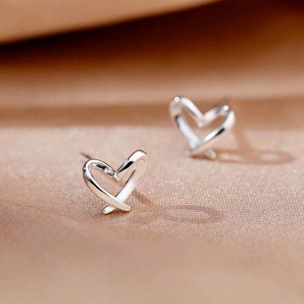 Woman wearing delicate 925 sterling silver open heart stud earrings