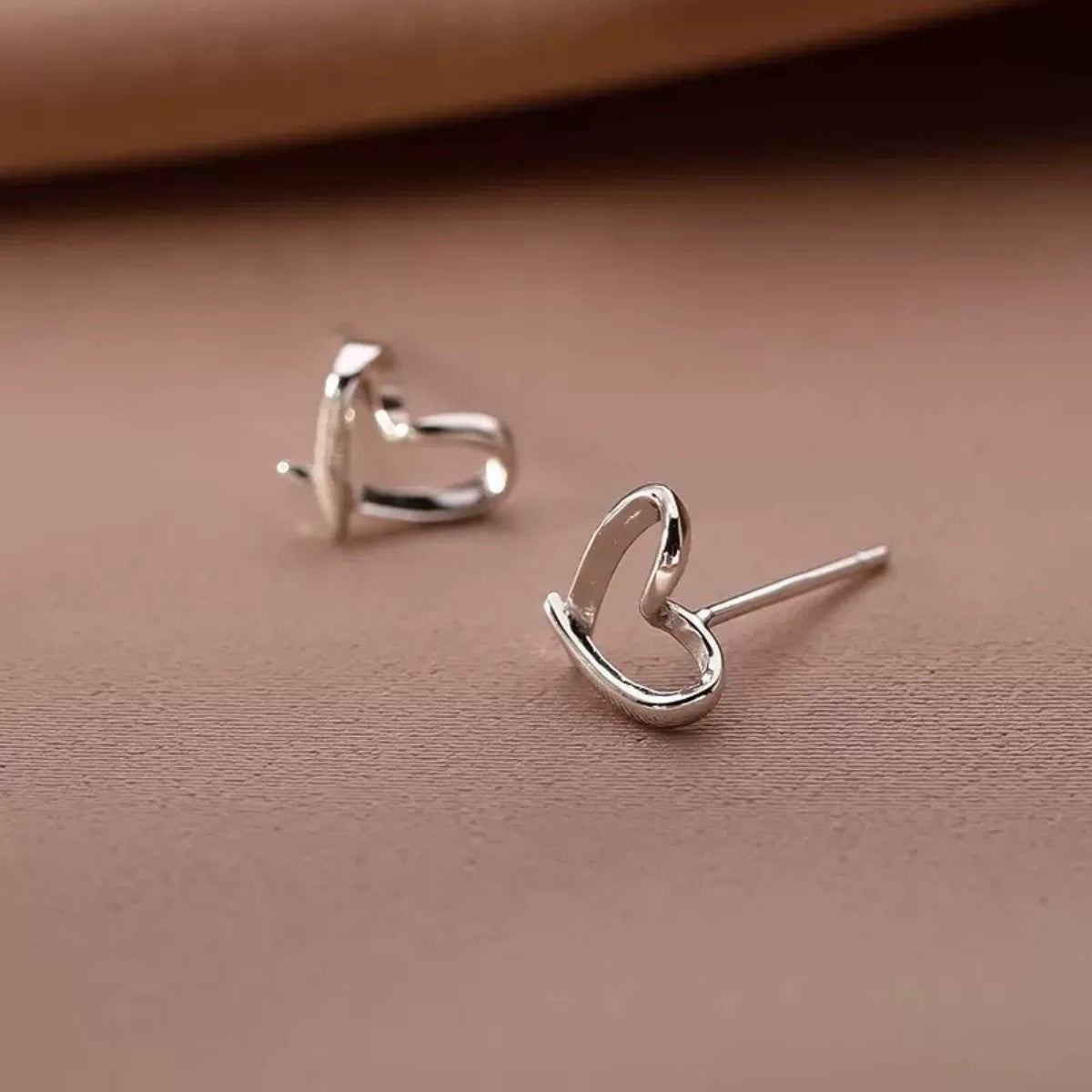 Woman wearing delicate 925 sterling silver open heart stud earrings
