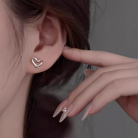 Woman wearing delicate 925 sterling silver open heart stud earrings