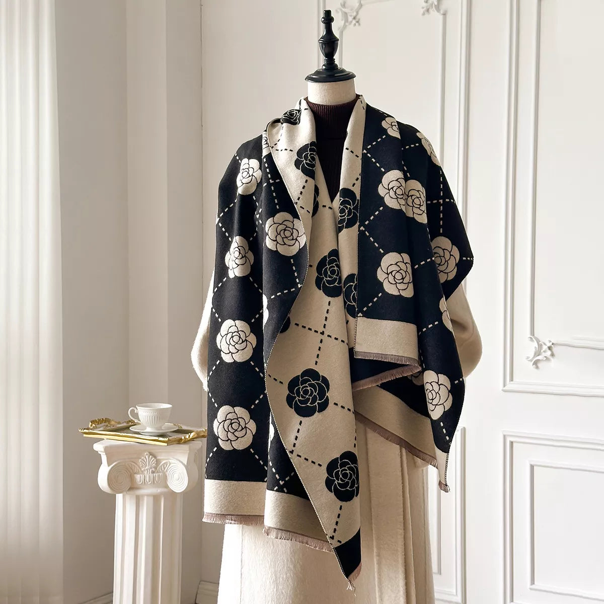 Floral wrap scarf with elegant geometric pattern draped over a neutral coat