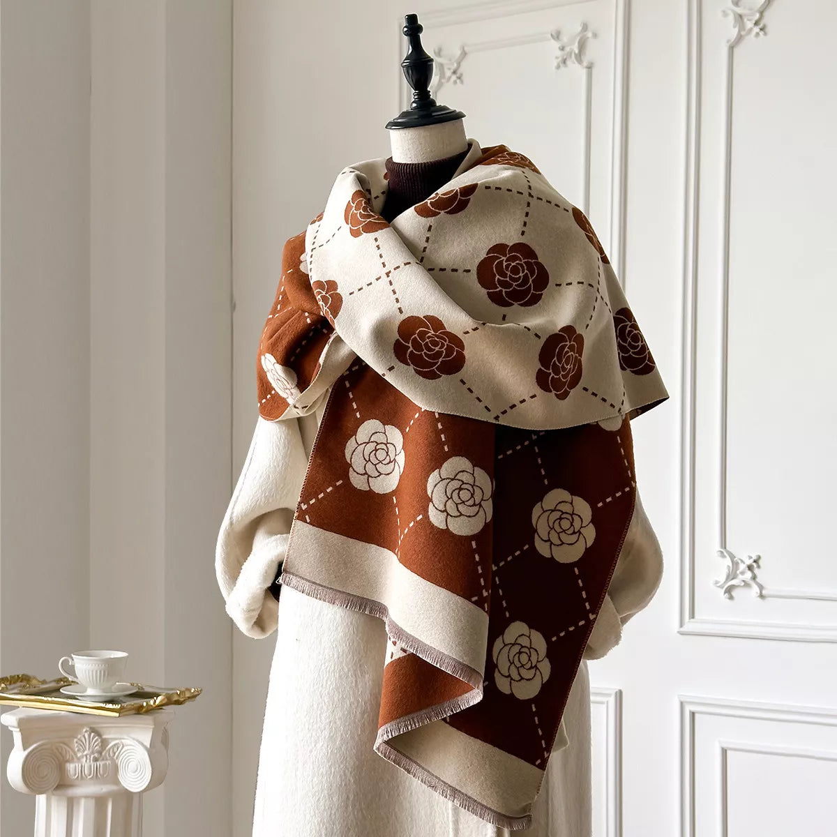 Floral wrap scarf with elegant geometric pattern draped over a neutral coat