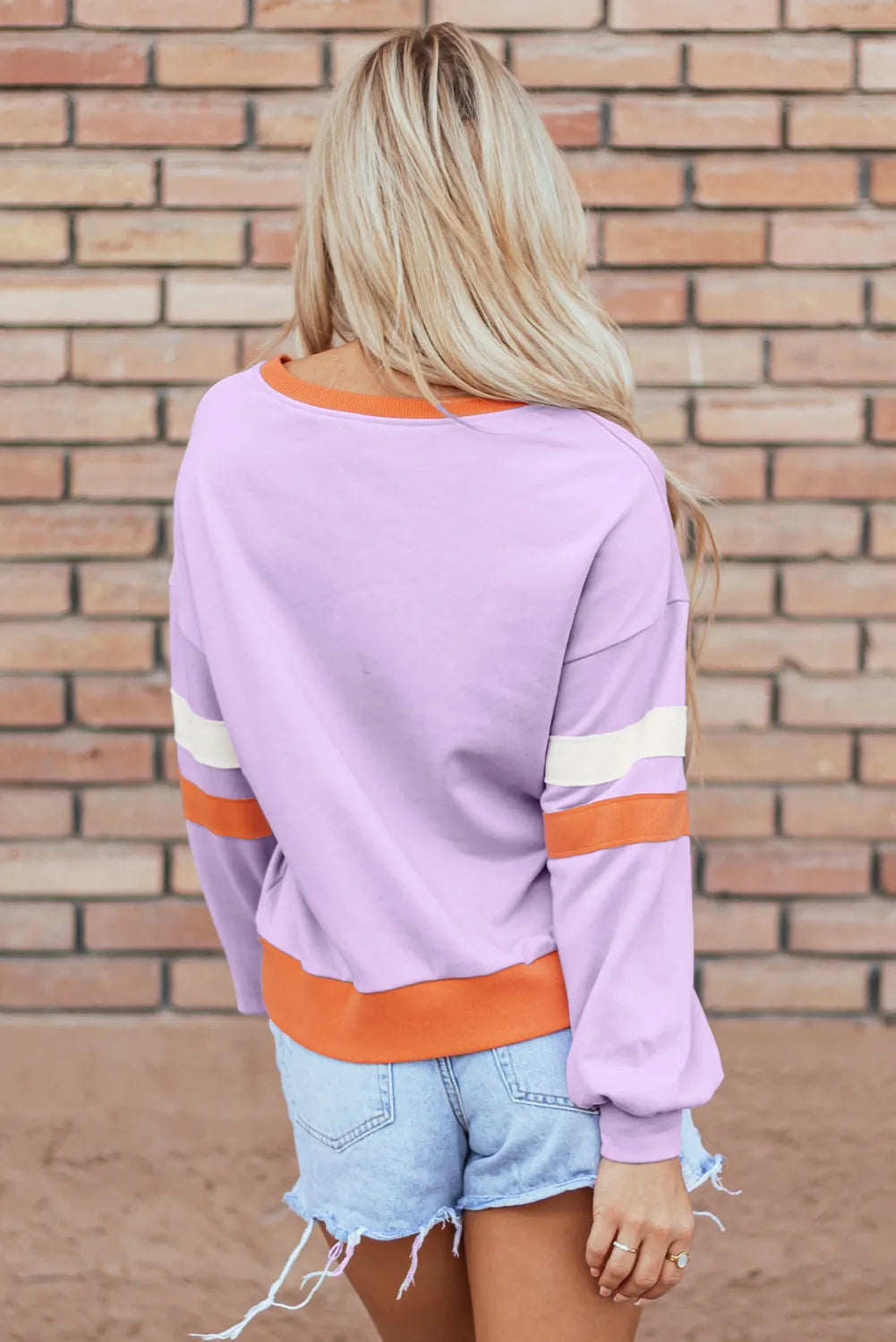 Woman wearing a lilac sweatshirt with a glittery orange checkered pumpkin and the phrase “Hello Pumpkin,” styled with denim shorts — cozy fall sweatshirt from A Whimsical Affair.