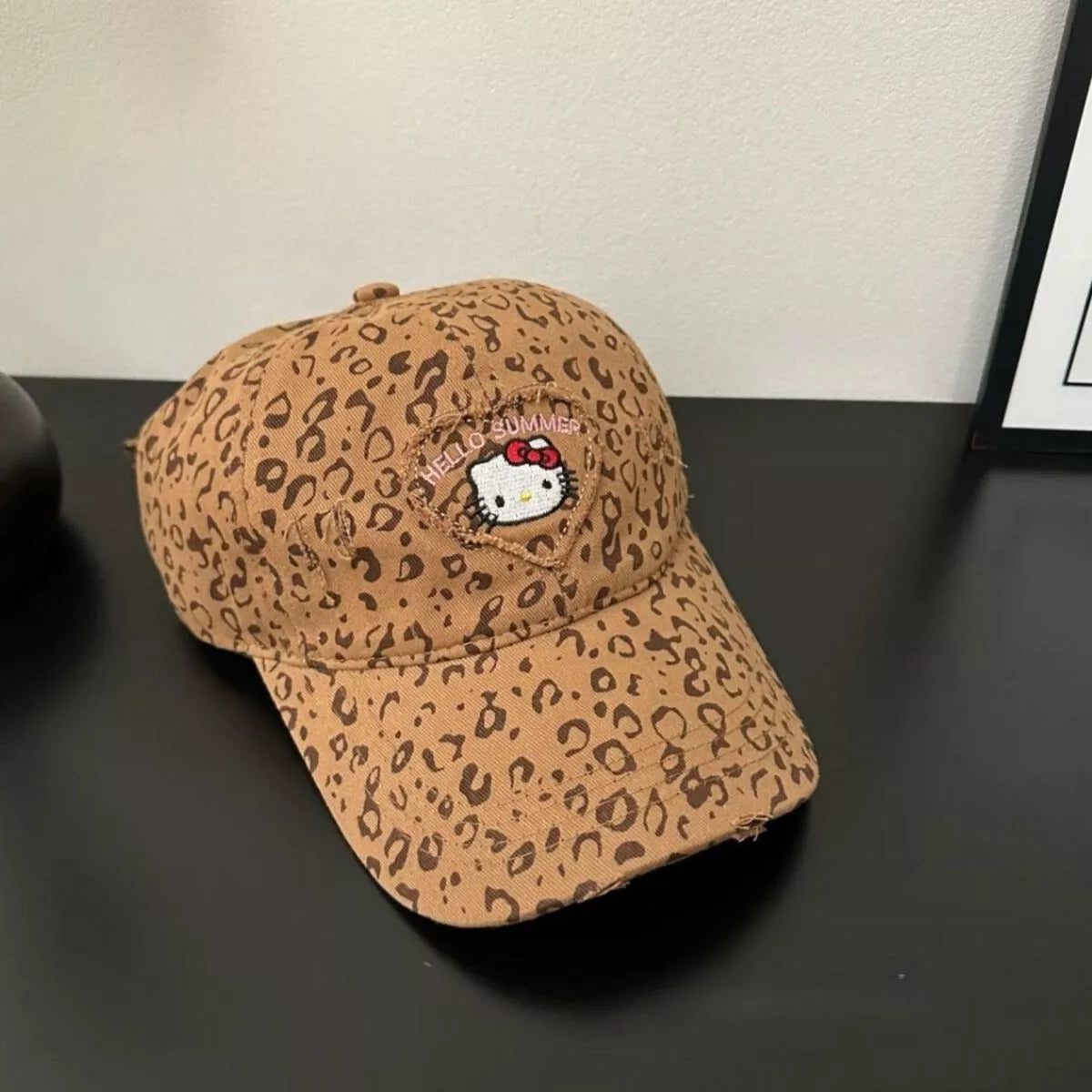 Tan leopard print cotton baseball cap with two-tone brim and embroidered Hello Summer kitty patch on the front.