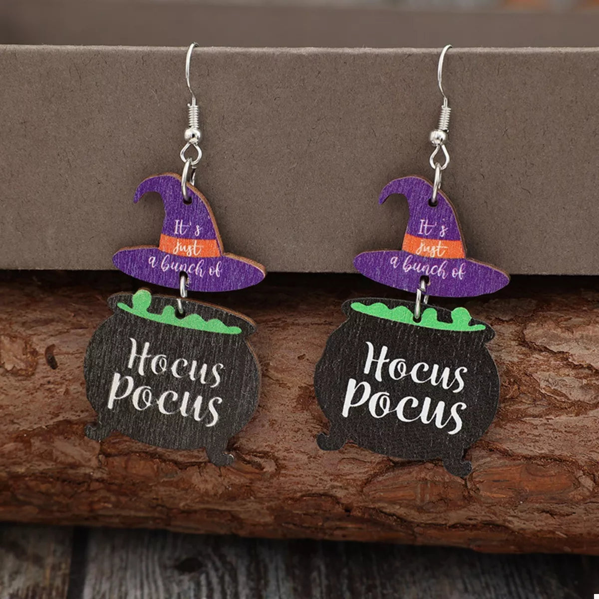 Close-up of Hocus Pocus Cauldron Earrings featuring black cauldrons with green potion and purple witch hats reading “It’s just a bunch of” — Halloween jewelry from A Whimsical Affair.