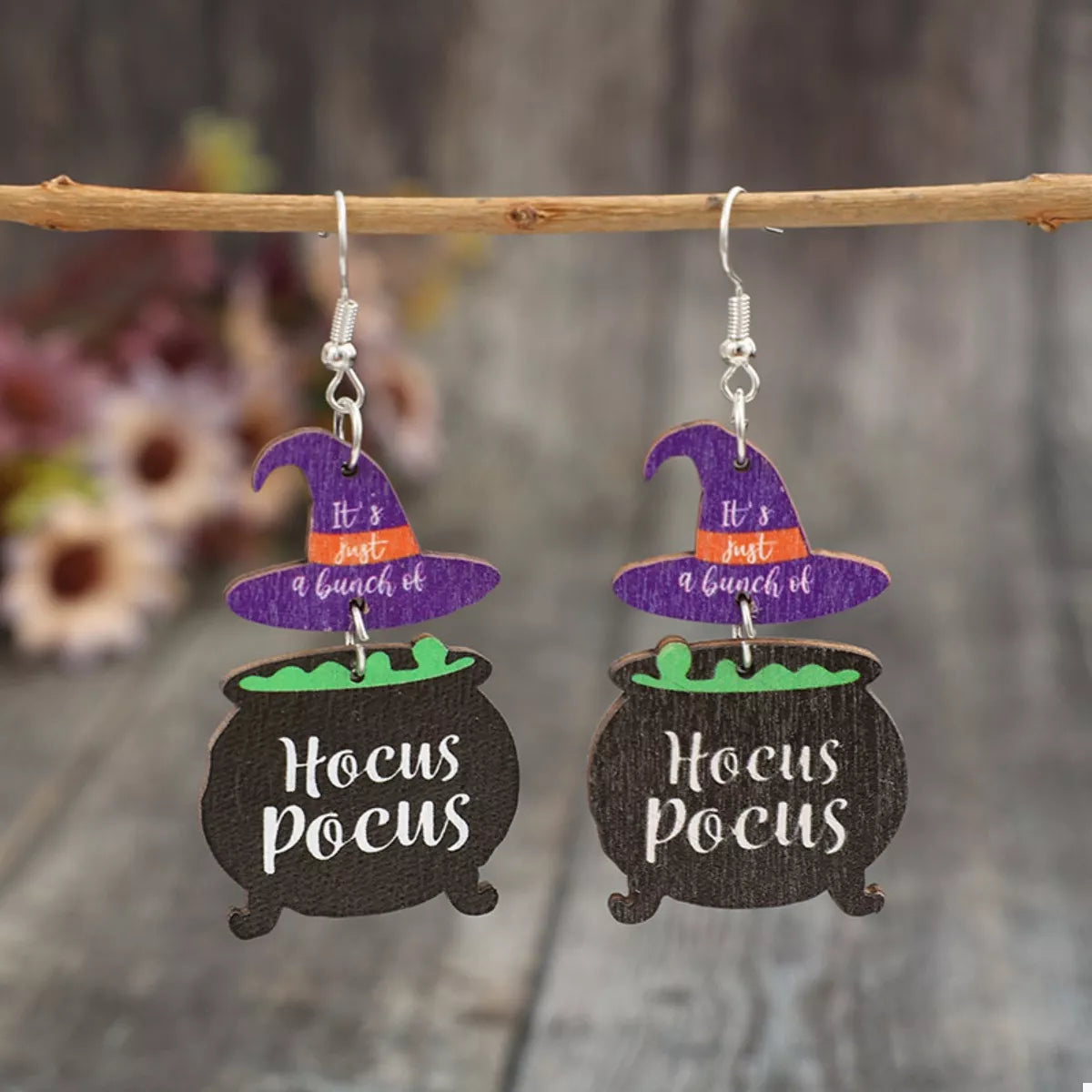 Close-up of Hocus Pocus Cauldron Earrings featuring black cauldrons with green potion and purple witch hats reading “It’s just a bunch of” — Halloween jewelry from A Whimsical Affair.