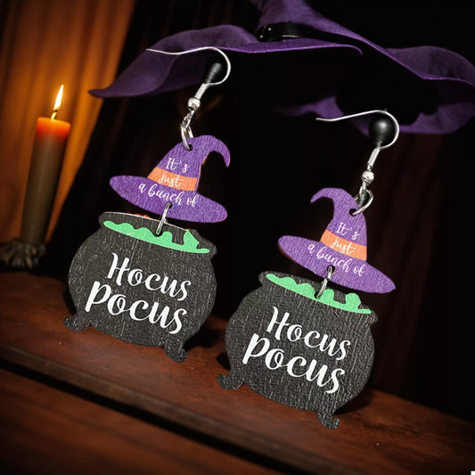 Close-up of Hocus Pocus Cauldron Earrings featuring black cauldrons with green potion and purple witch hats reading “It’s just a bunch of” — Halloween jewelry from A Whimsical Affair.
