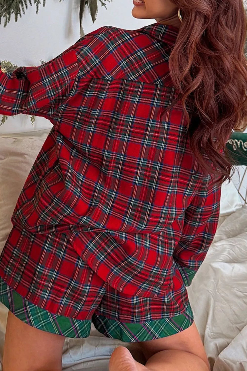 Model wearing red plaid button-down pajama set with green contrast pocket and shorts.