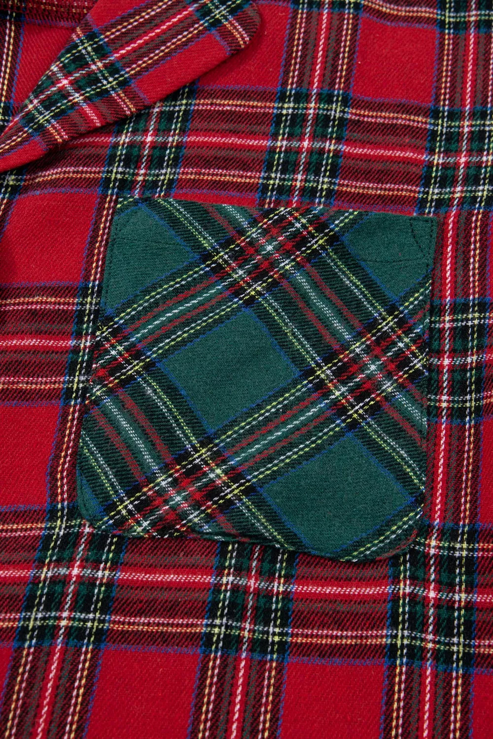 Model wearing red plaid button-down pajama set with green contrast pocket and shorts.