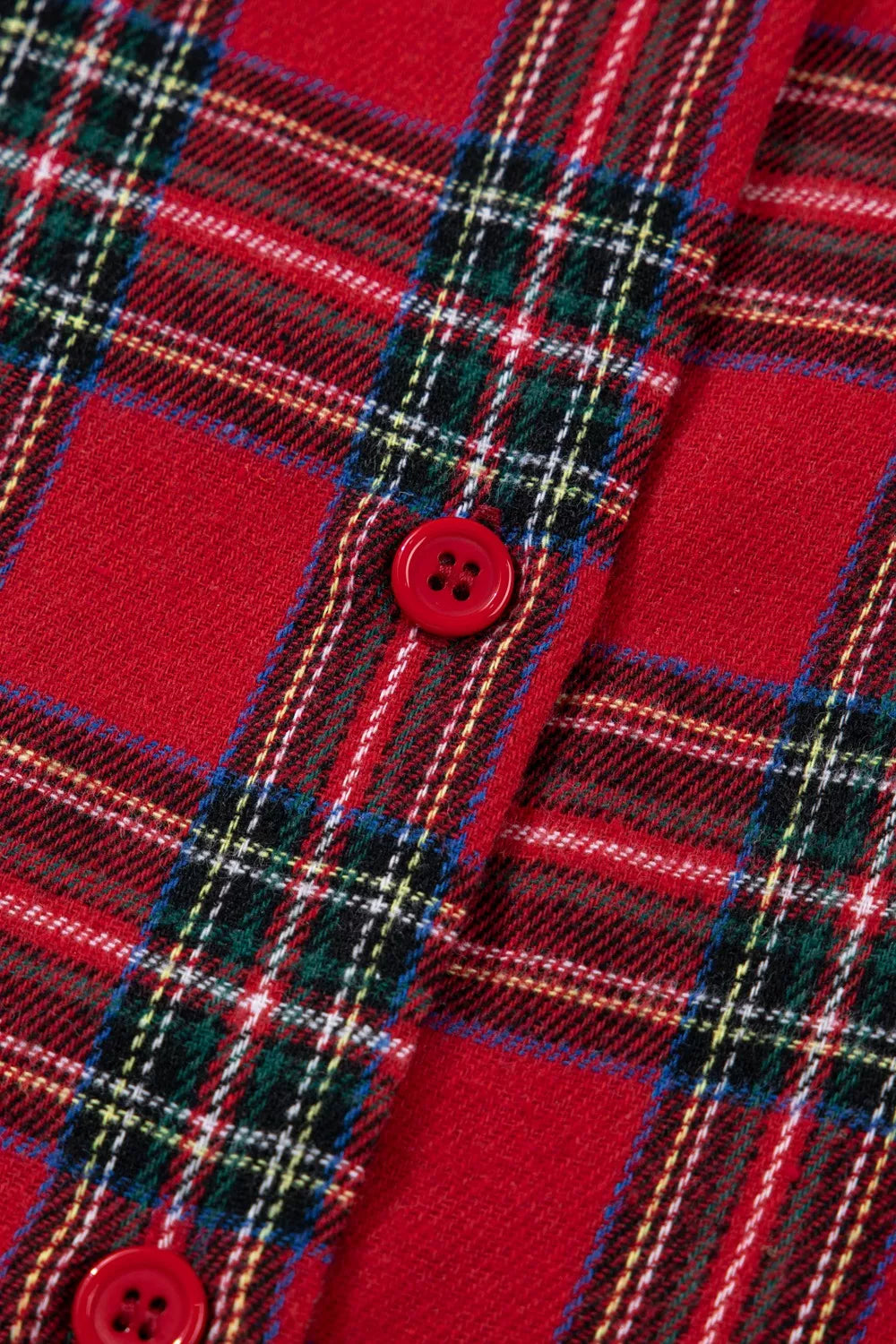 Model wearing red plaid button-down pajama set with green contrast pocket and shorts.