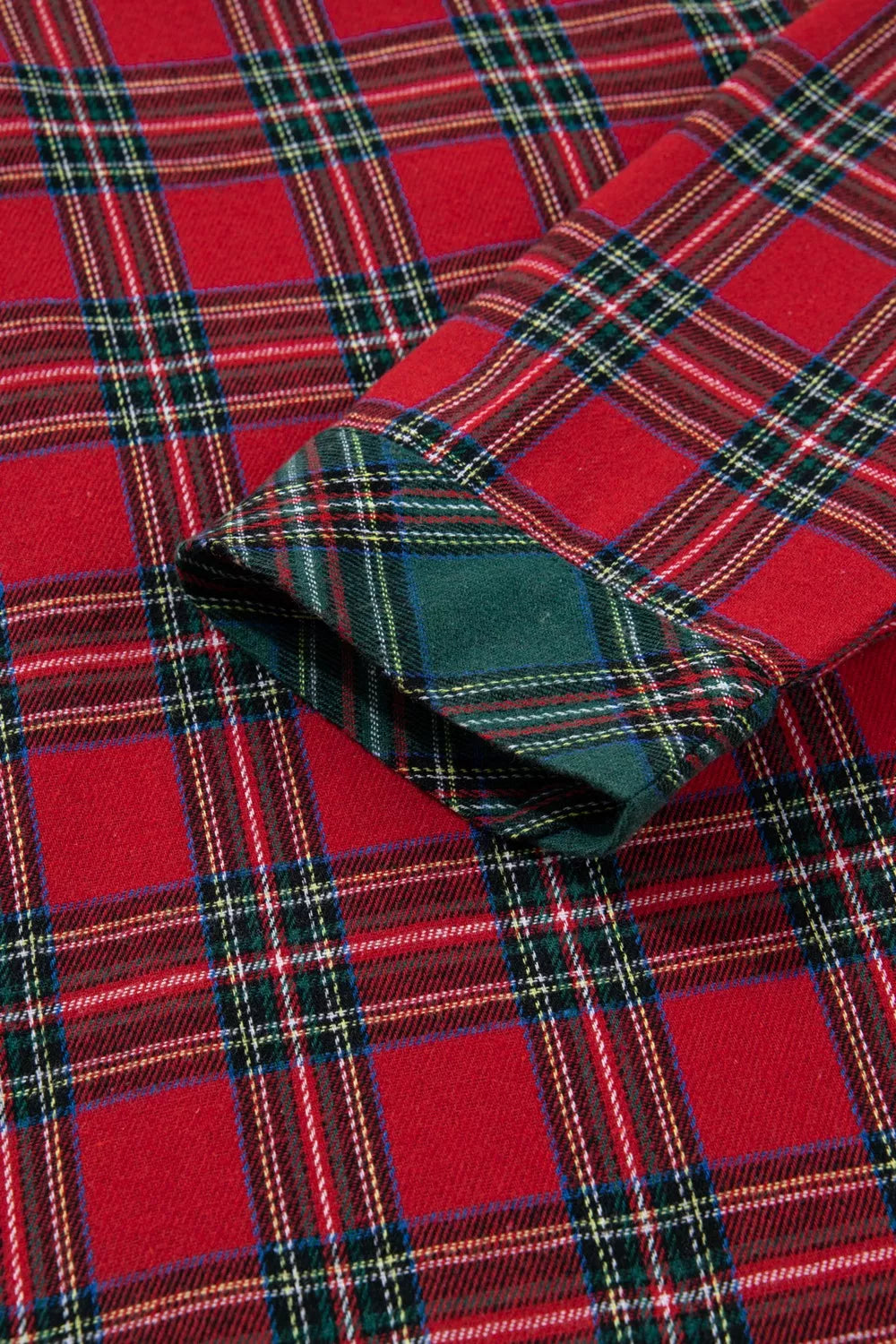 Model wearing red plaid button-down pajama set with green contrast pocket and shorts.