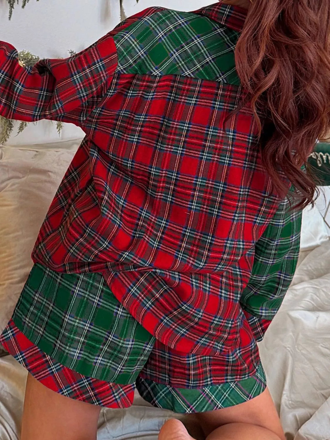 Model wearing green and red plaid button-down pajama set with red contrast pocket and shorts.