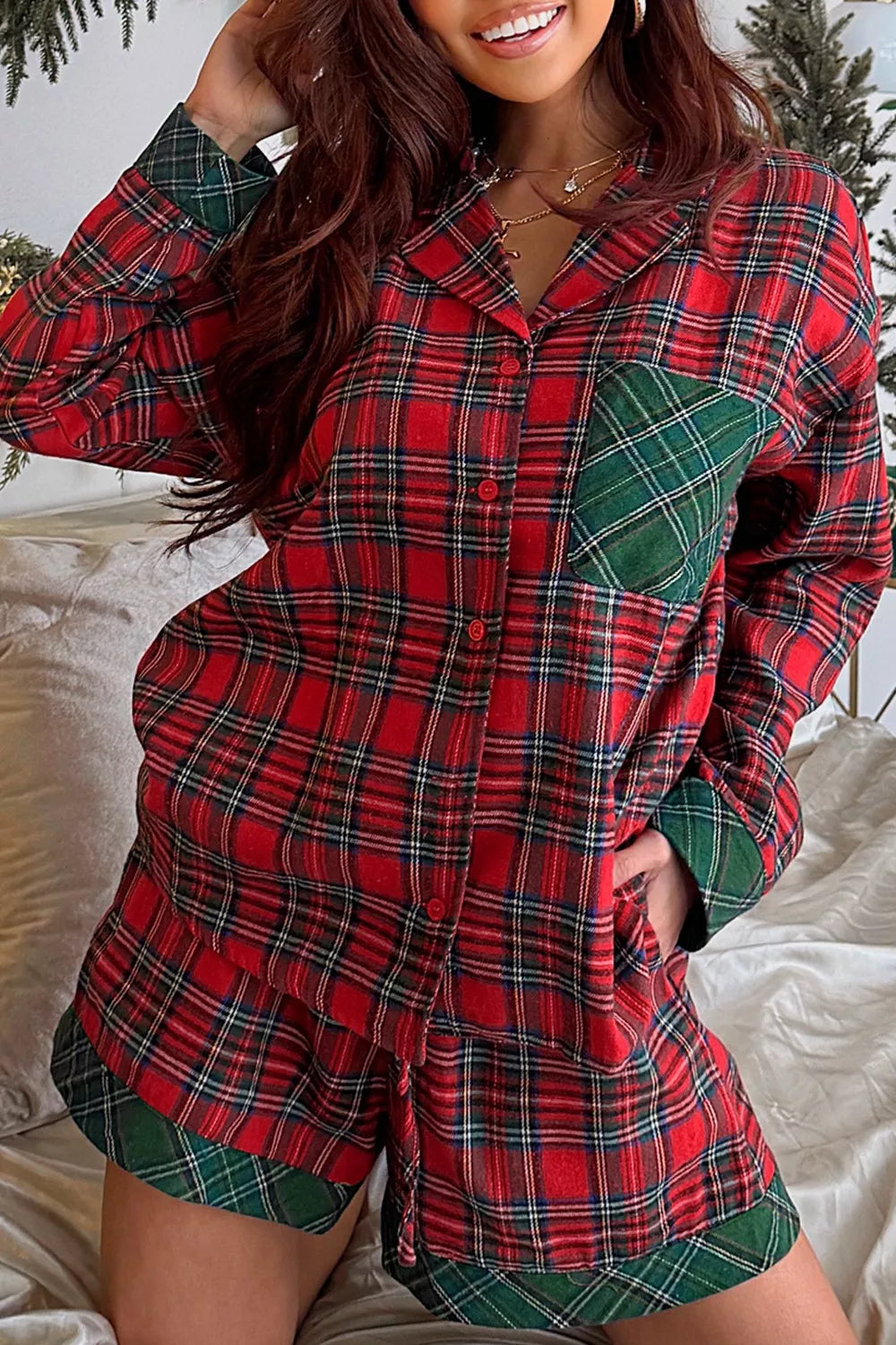 Model wearing red plaid button-down pajama set with green contrast pocket and shorts.