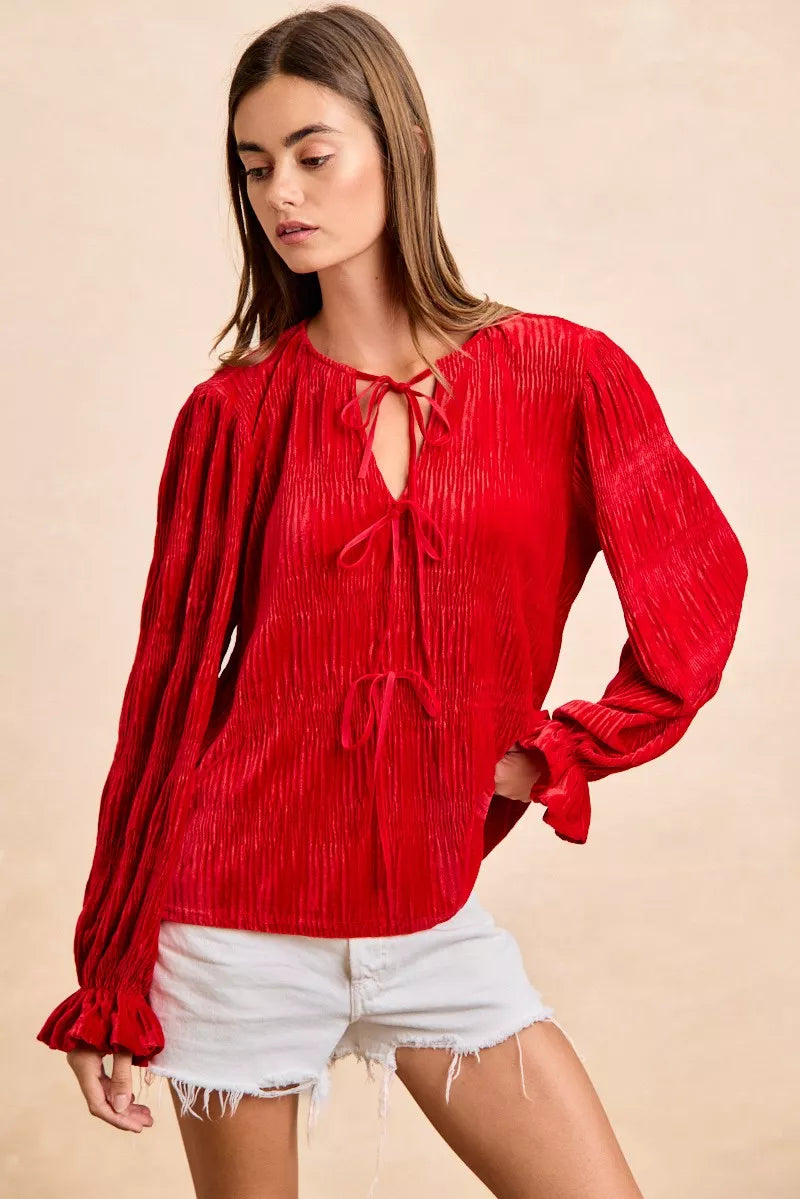 Red velvet long-sleeve blouse with tie-front bows and a neck drop design.