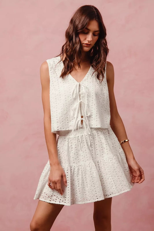 Ivory floral eyelet lace two-piece set with tie-front vest top and tiered mini skirt.