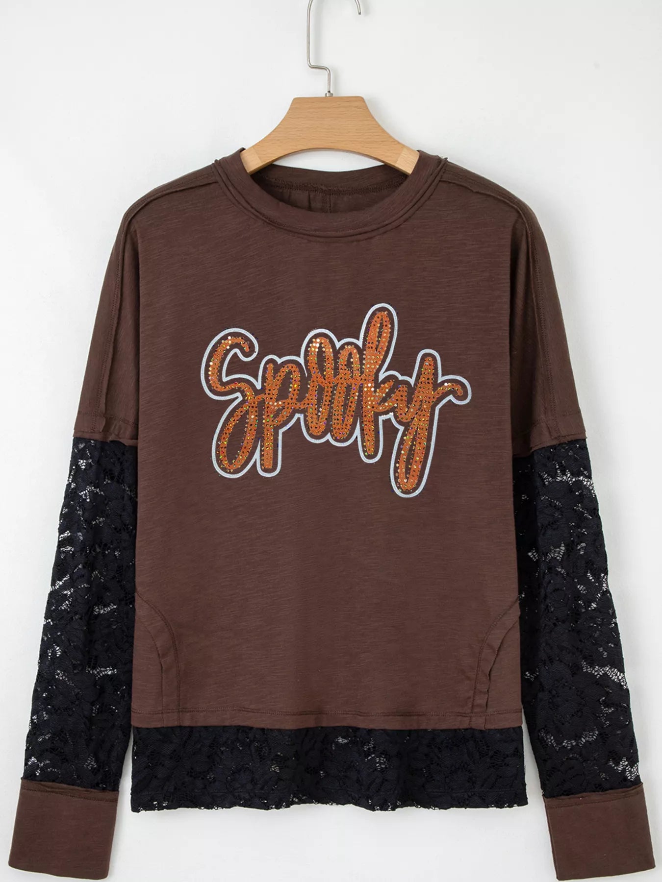 Woman wearing an oversized brown “Spooky” sequin graphic top with black lace sleeves and hem — layered Halloween tee from A Whimsical Affair.